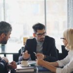 Business professionals engaged in a meeting at a café, sharing ideas and discussion.
